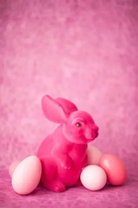 Pink Easter bunny with Easter eggs in front of pink background