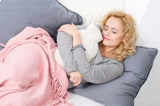 Woman lying on couch with hot water bottle