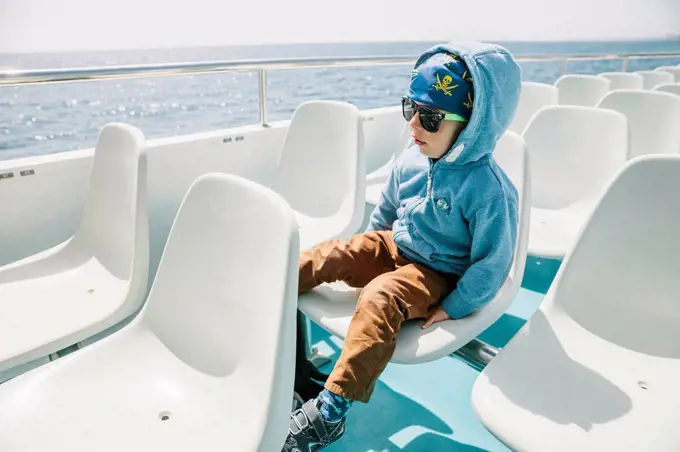 Spain, Mallorca, little boy with sunglasses and pirate bandana sitting on a tourist boat