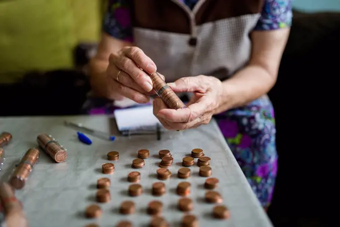 Elderly woman counting money, making stacks of Euro cents