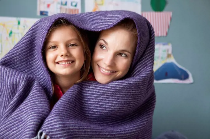 Portrait of mother and little daughter with woollen blanket