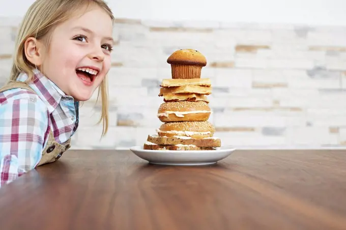 Portrait of smiling little girl with stack of baked goods