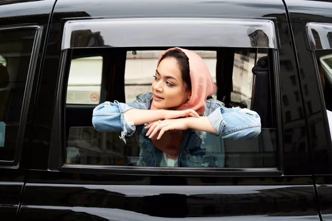 UK, England, London, young woman wearing hijab looking out of a taxi
