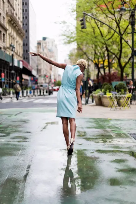 USA, New York, young blonde african-american woman walking in puddle