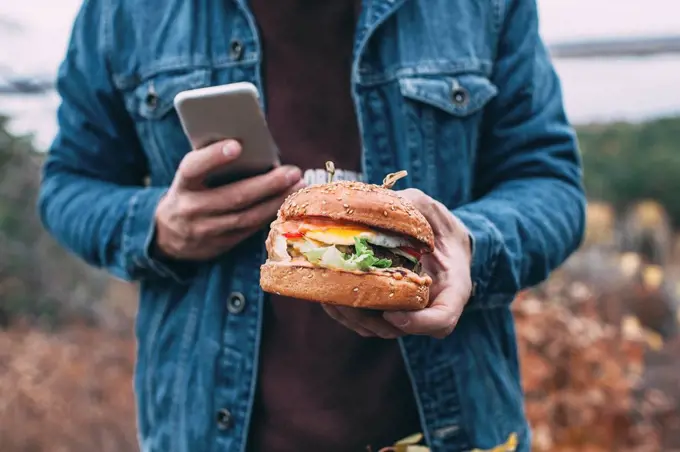 Man with burger and smartphone