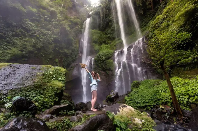 Indonesia, Bali, young woman standing at Sekumpul waterfall