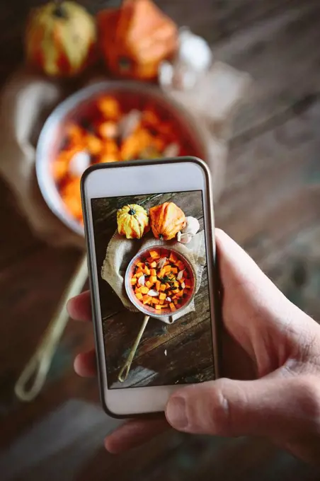 Taking photo of casserolle of pumpkin dish with smartphone