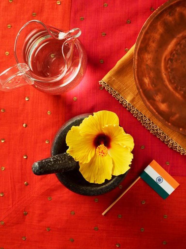 Hibiscus Flower in Mortar with Pestle, Jug of Water and Indian flag on Red Background,03/30/2011