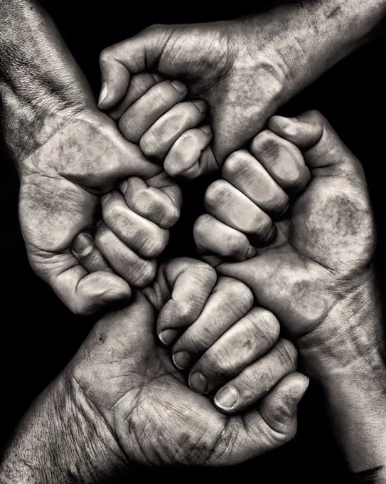 Four Clenched Hands against Black Background
