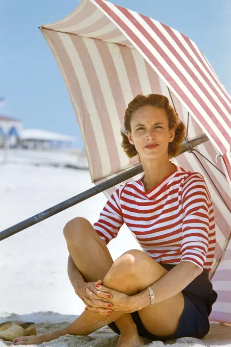 Casual Woman and Beach Umbrella with Red Stripes, Hamptons, Long Island, New York, USA, Toni Frissell Collection, August 1955