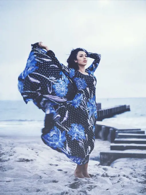 Portrait of Woman in Black & Blue Floral Print Dress on Beach, Dress Blowing in Wind