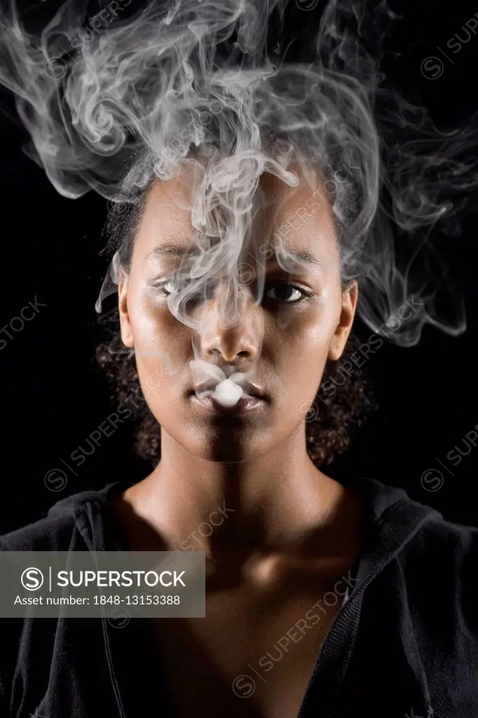 Young, dark-skinned woman smoking a cigarette, cigarette smoke