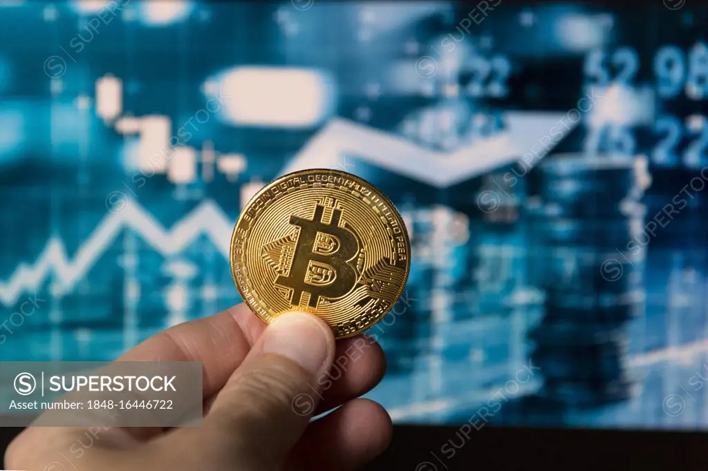 Symbol image digital currency, physical coin Bitcoin, woman holding Bitcoin in her hand, in the background stock market price