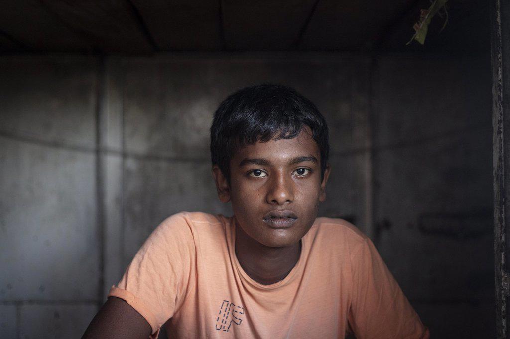 A sailor is sitting at the entrance of his sleeping cabin on a freighter in the port of Mongla, Sundarbans, Bangladesh, Asia
