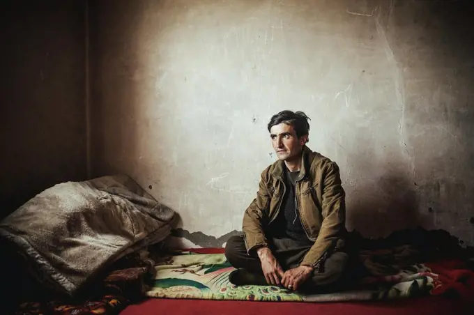 Man sitting on a blanket, stone house, Bozai Gumbaz, Wakhan corridor, Afghanistan, Asia