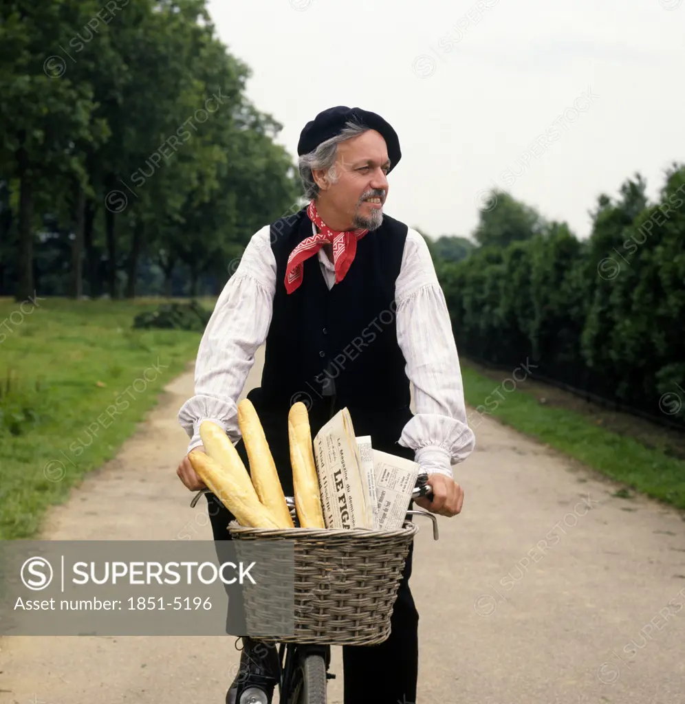Frenchman cycling down country lane with French Bread Baguettes and Newspaper