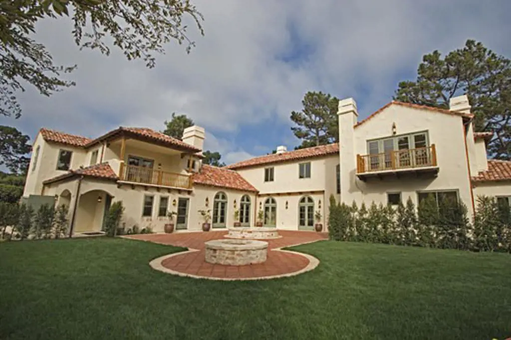 Exterior of a SPANISH STYLE LUXURY HOME with stucco walls and red tile roof 