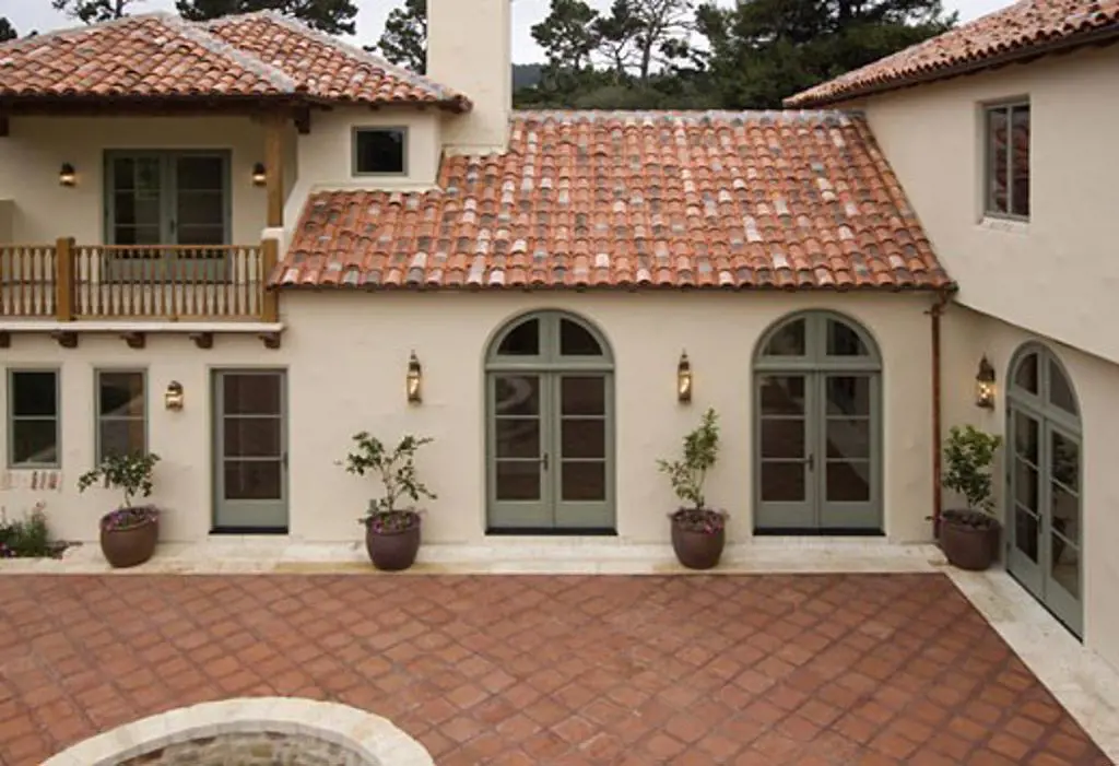 Exterior of a SPANISH STYLE LUXURY HOME with stucco walls a red tile roof and MEXICAN TILE PATIO
