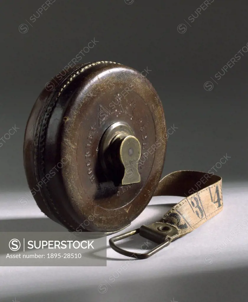 Flexible tape measure made of a cloth tape on a reel with measurements in  feet and inches on one side and links on the other. It was made by John  Rabo 