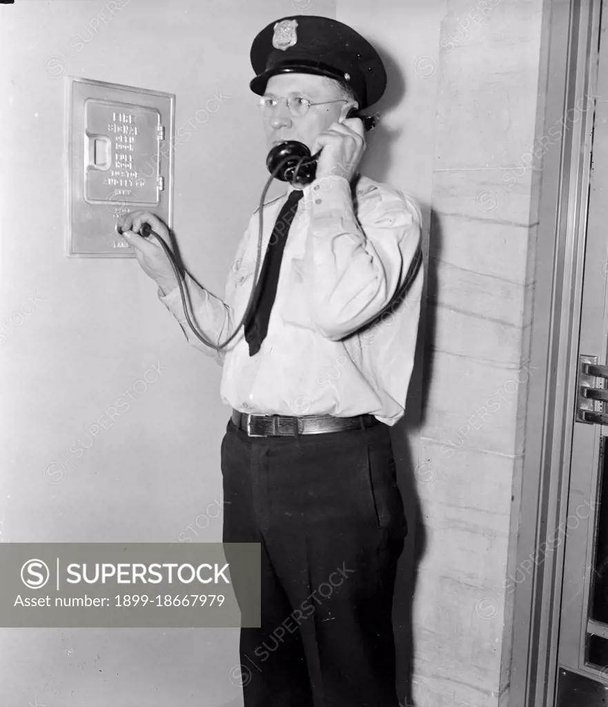 F.B.I. guard reports in. Washington, D.C., Aug 4. Officer Ray D. Buckingham using a plug-in telephone, which every guard carries as part of his regular equipment circa 1937.