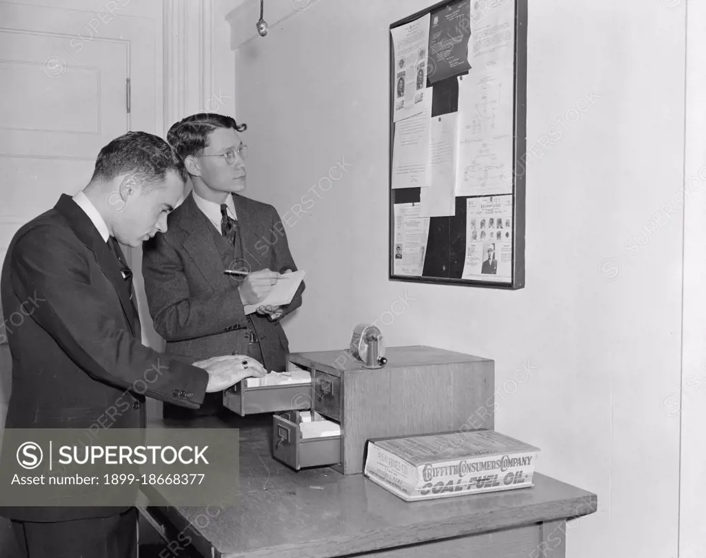 Employees of the Secret Service checking over bulletin board getting the latest criminal news circa 1938.