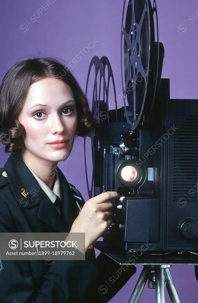 1979 - A female U.S. Army audiovisual technician operates a 16mm film projector. 
