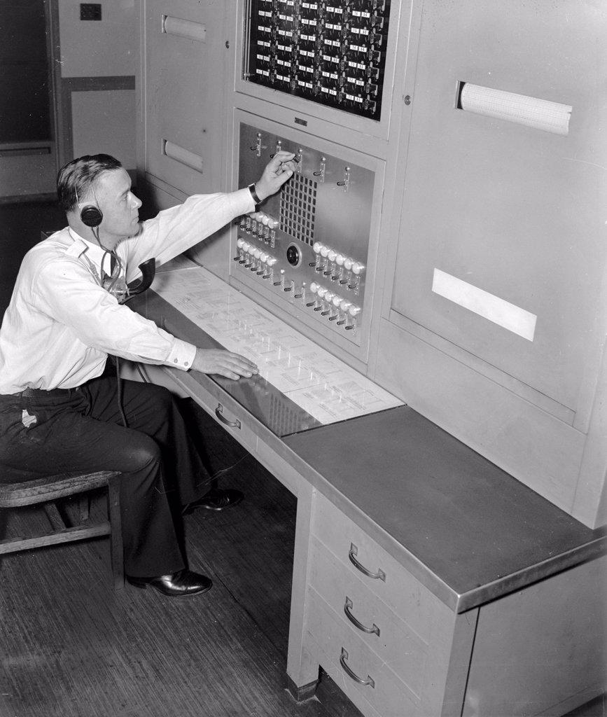 Officer William L. Good is shown at the FBI 'Patrol Board' in the Captain of the Guard's office which maintains direct communication with every watch station and substation throughout the huge FBI Headquarters building circa 1937.
