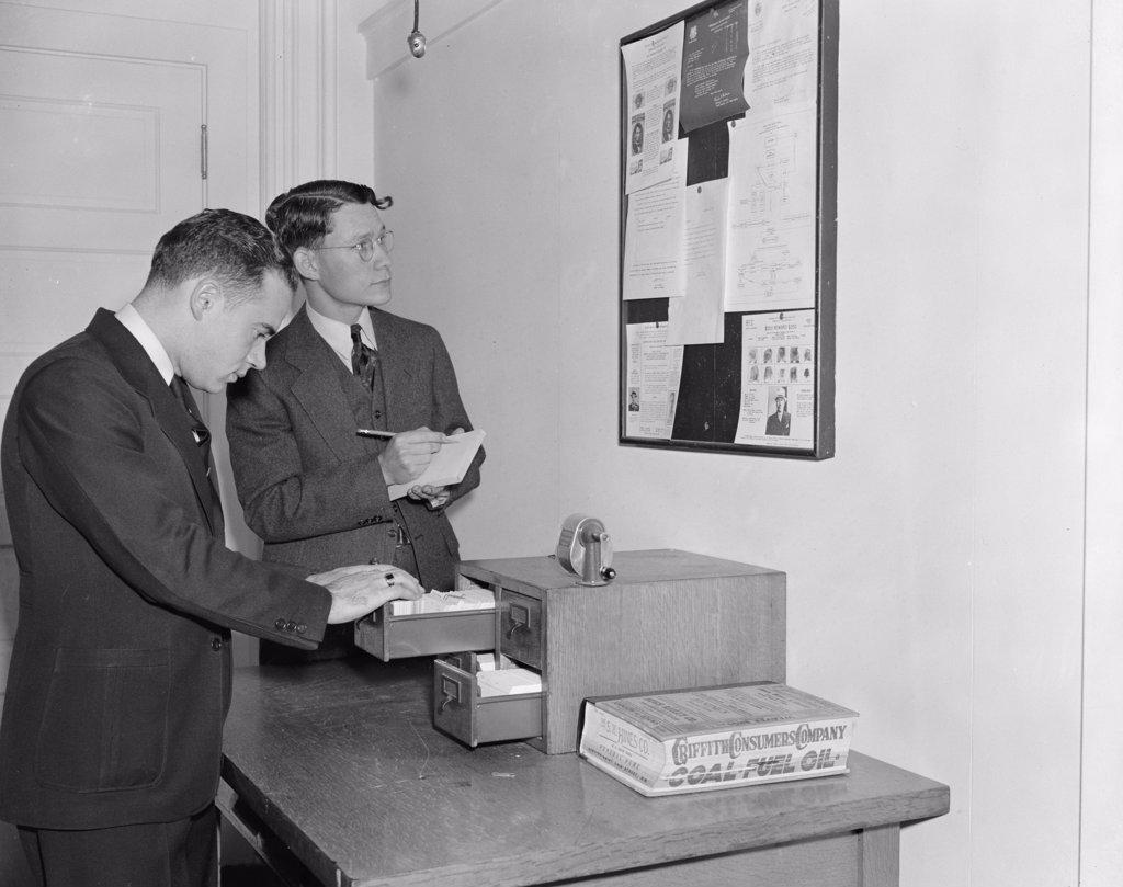 Employees of the Secret Service checking over bulletin board getting the latest criminal news circa 1938.