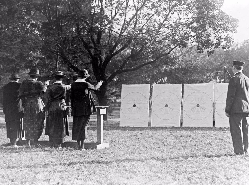 Four policewomen shooting at targets, as a policeman watches ca. 1909.