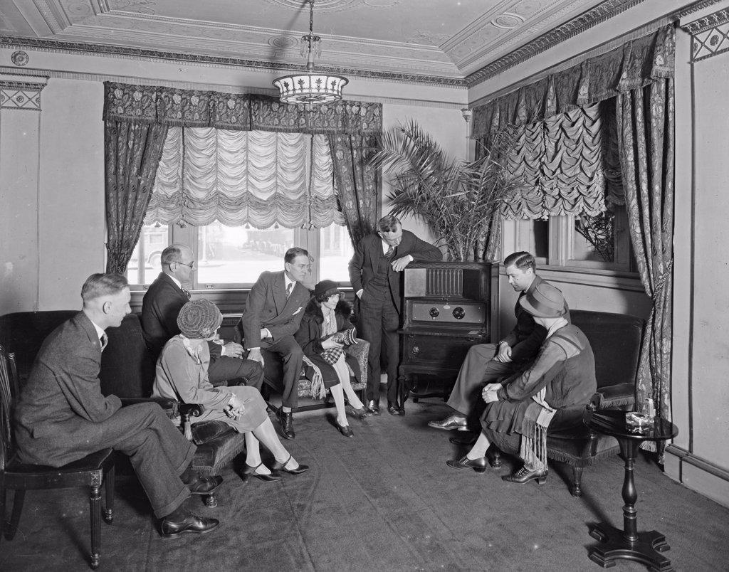 Thomas R. Shipp Company group listening to a radio in a room at the Hamilton Hotel ca. between 1910 and 1935.