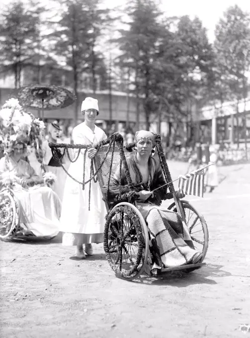 Wounded WW I soldiers at Walter Reed Hospital participate in a 4th of July wheel chair parade circa 1919 .