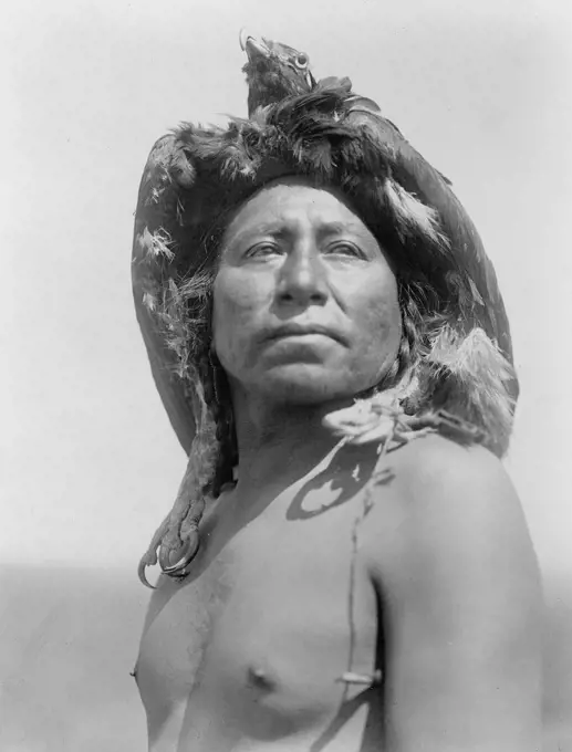 Edward S. Curtis Native American Indians - Apsaroke shaman, head-and-shoulders portrait, facing front, wearing eagle headdress ca. 1908. 