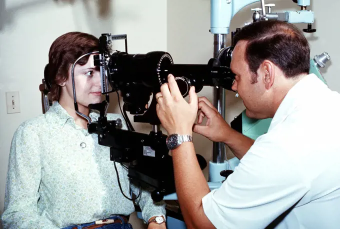 1976 - A female has her eyes checked by a doctor who is using an Ophthalmoscope. 