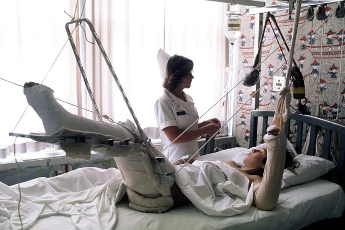 1976 - A nurse adjusts the intravenous feeding line on a patient. 