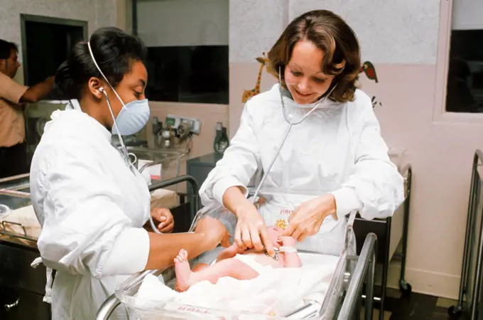 1976 - Members of the Medical Corps, listen to the heart of a normal care newborn baby, as part of infant examinations in the Infant Ward at Womack Army Hospital. 
