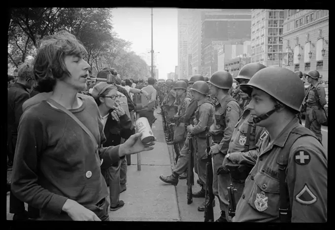 Young hippie standing in front of a row of National Guard soldiers, across the street from the Hilton Hotel at Grant Park, during the Democratic National Convention, Chicago, IL, 08/29/1968. (Photo by Warren K Leffler)