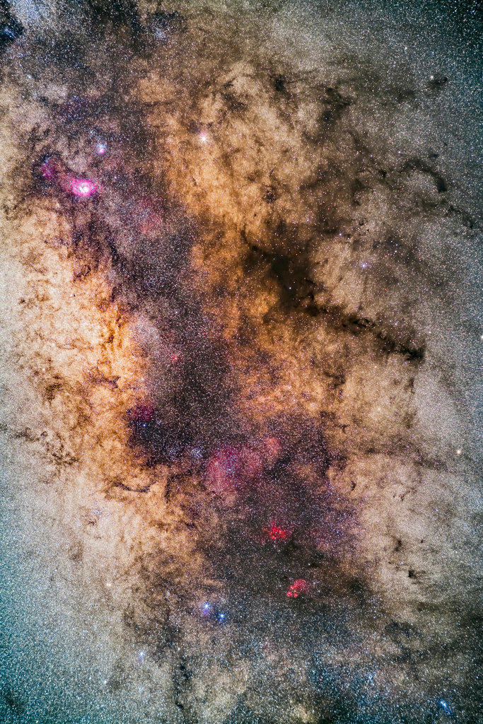 The Milky Way through the region of the tail of Scorpius and up into Sagittarius, photographed with it high in the sky from Australia. At bottom are the red nebulas of NGC 6334, the Cat’s Paw, and NGC 6357 (sometimes called the Lobster Nebula, for a “Paws and Claws” pairing). 

The clusters Messier 6 and Messier 7 are at left, below centre, with M7 lost in the star clouds of the Milky Way. The Galactic Centre lies at left centre. 

The Lagoon and Trifid Nebulas, M8 and M20, are at top left. Satu