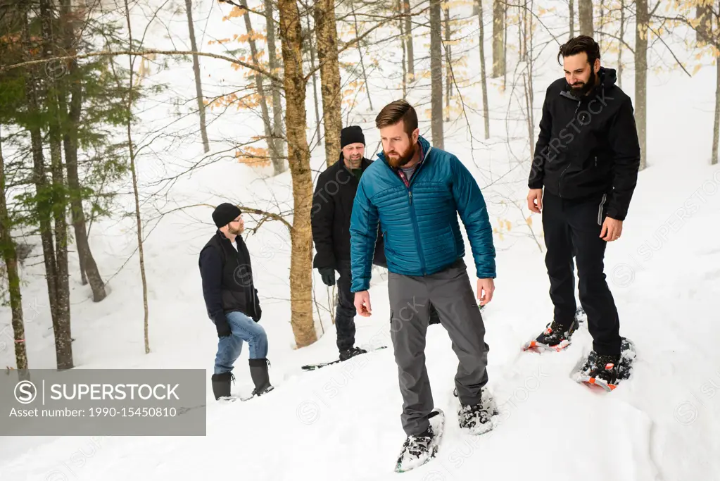 Group of friends (all late 30s) snowshoeing through the woods in winter. Mont Tremblant, Quebec, Canada