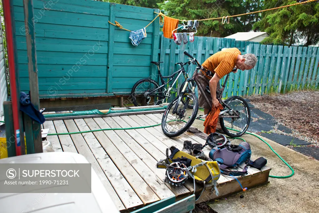 A middle aged man washing down his mountain bike after a muddy ride in Golden, BC