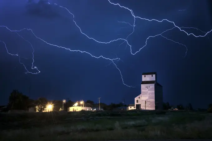 Storm with lightning over old grainery in rural Elkhorn, Manitoba, Canada