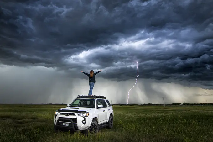 Self portrait on top of my truck with storm and lightning in the distance in rural Manitoba Canada
