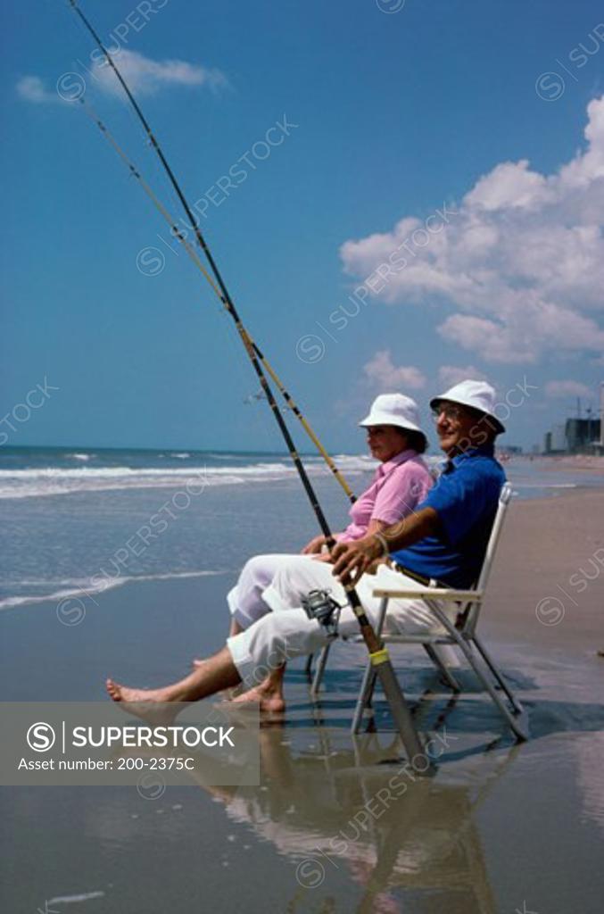 Stock Photo: 200-2375C Senior couple sitting on beach chairs with fishing rods