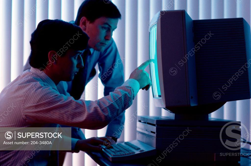 Stock Photo: 204-3480A Two businessmen using a computer in an office