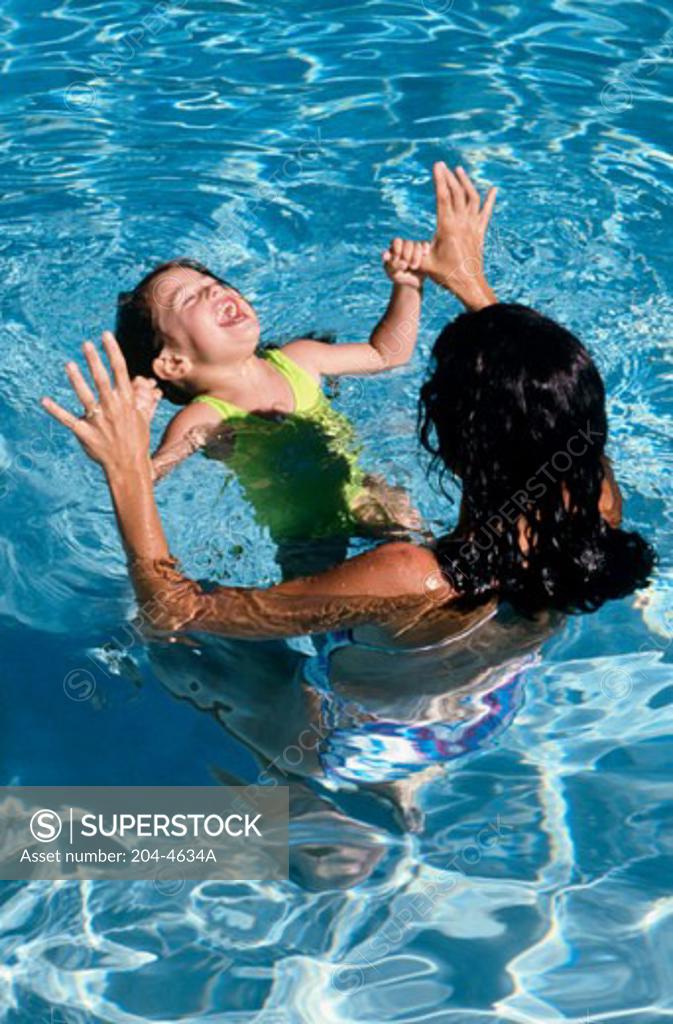 Stock Photo: 204-4634A High angle view of a girl holding her mother's thumbs in a swimming pool