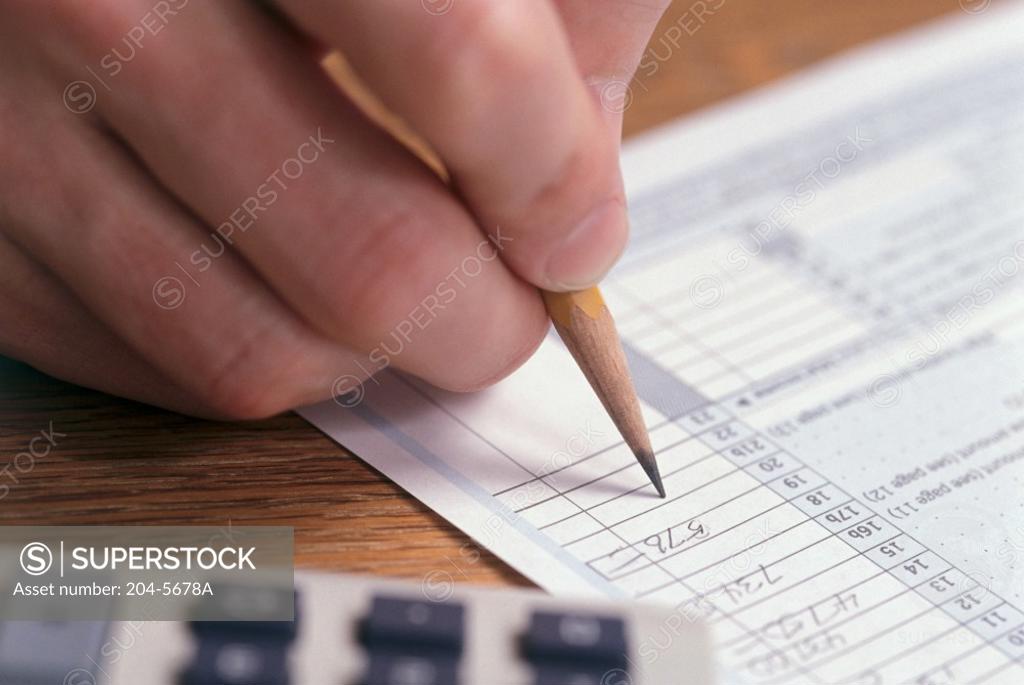 Stock Photo: 204-5678A Close-up of a person's hand writing on a tax form