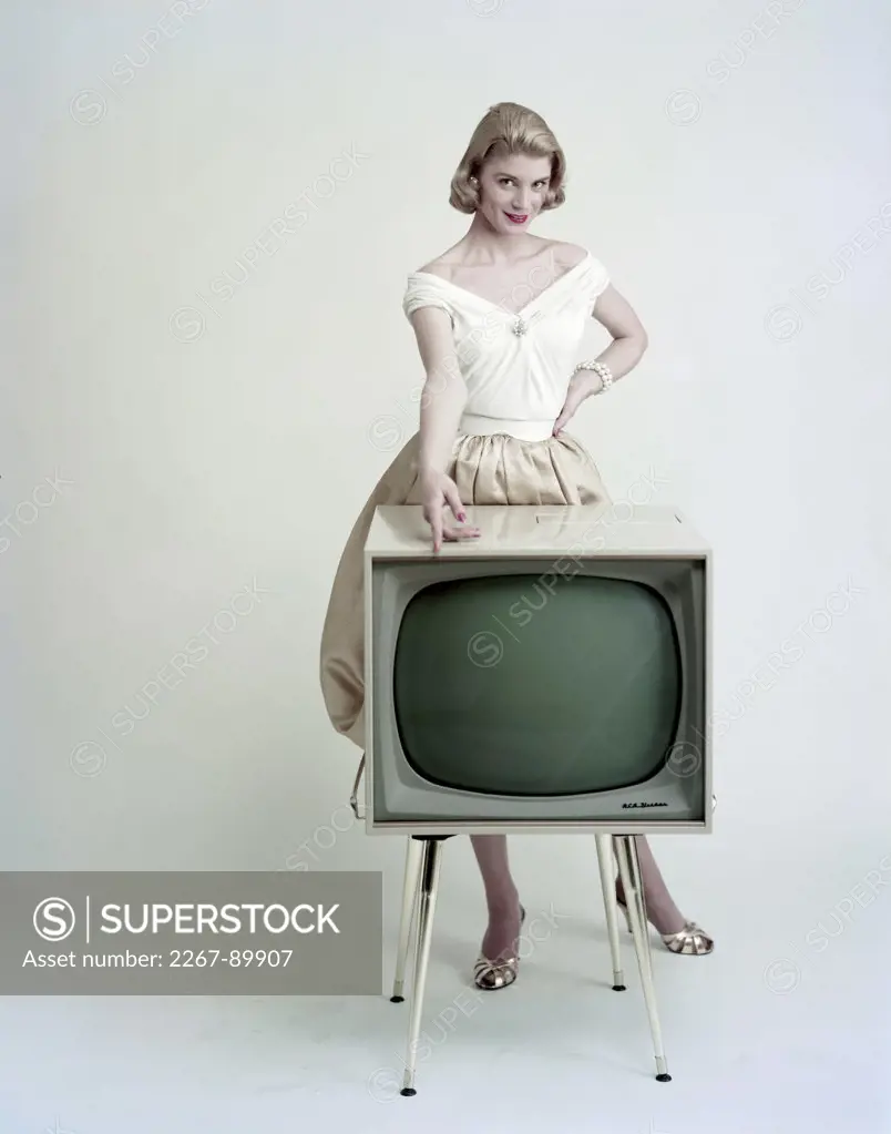 Portrait of a young woman standing behind a television and smiling