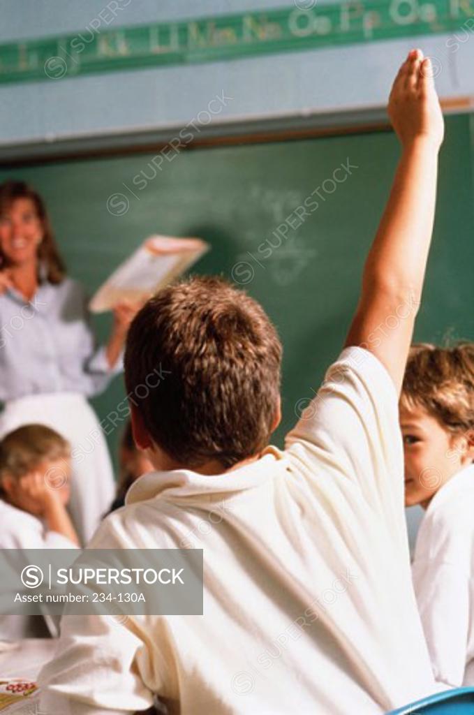 Stock Photo: 234-130A Rear view of a schoolboy with his hand raised in a classroom