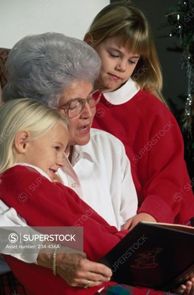 Stock Photo: 234-436A Senior woman with her two granddaughters reading a book
