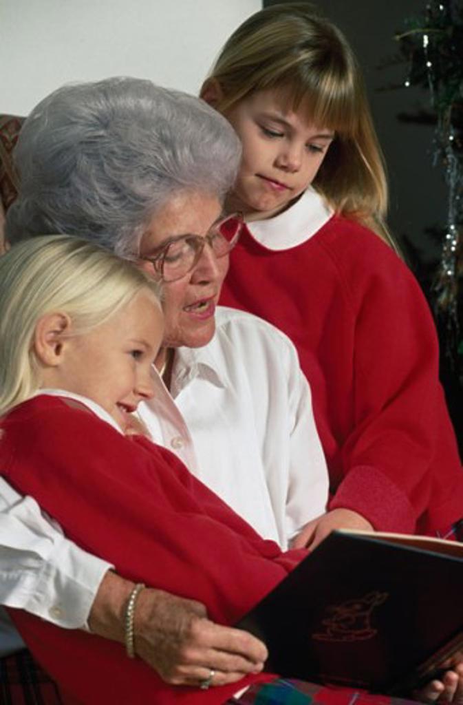 Senior woman with her two granddaughters reading a book
