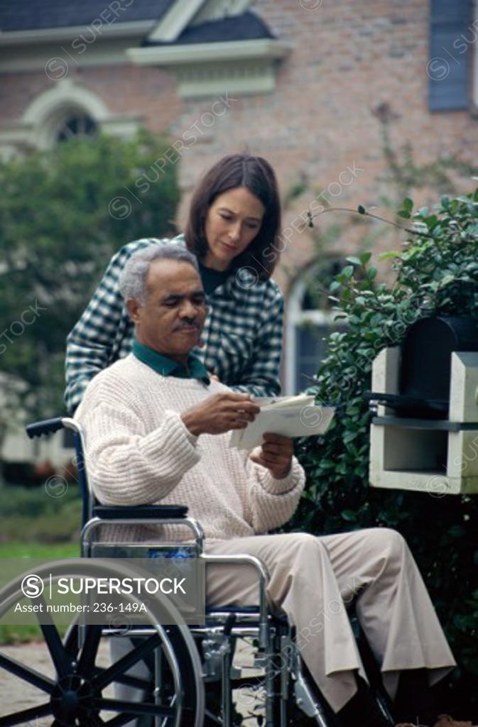 Stock Photo: 236-149A Mid adult couple near a mailbox looking at mail